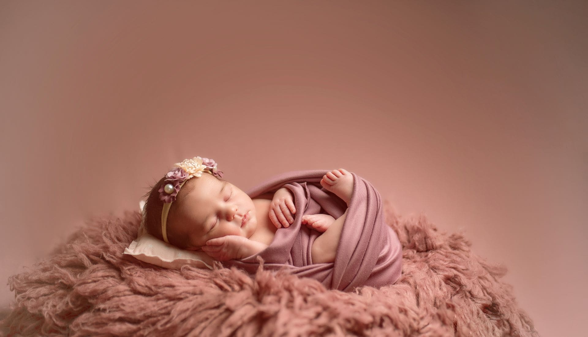 Foto bebé recién nacido con fondo rosa en un sesión de fotos de Alejandra Mato Fotografía