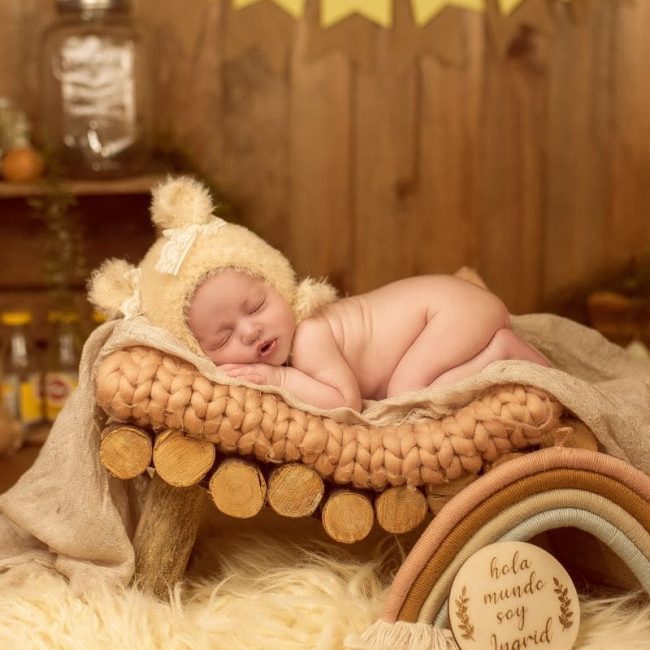 Foto bebé recién nacido con fondo amarillo y madera en un sesión de fotos de Alejandra Mato Fotografía