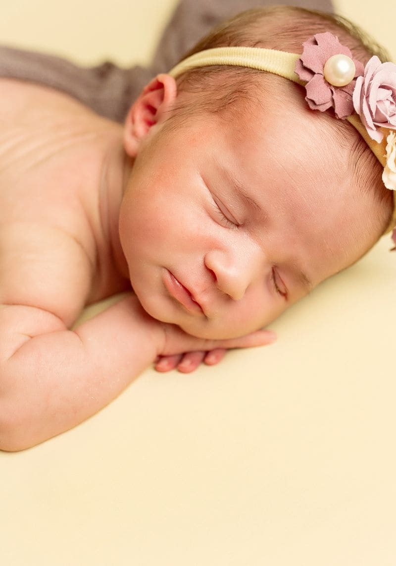 Foto bebé recién nacido con fondo amarillo en un sesión de fotos de Alejandra Mato Fotografía